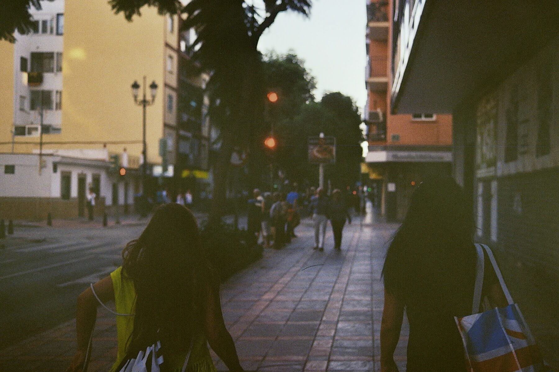 Two people walking up a street in the evening