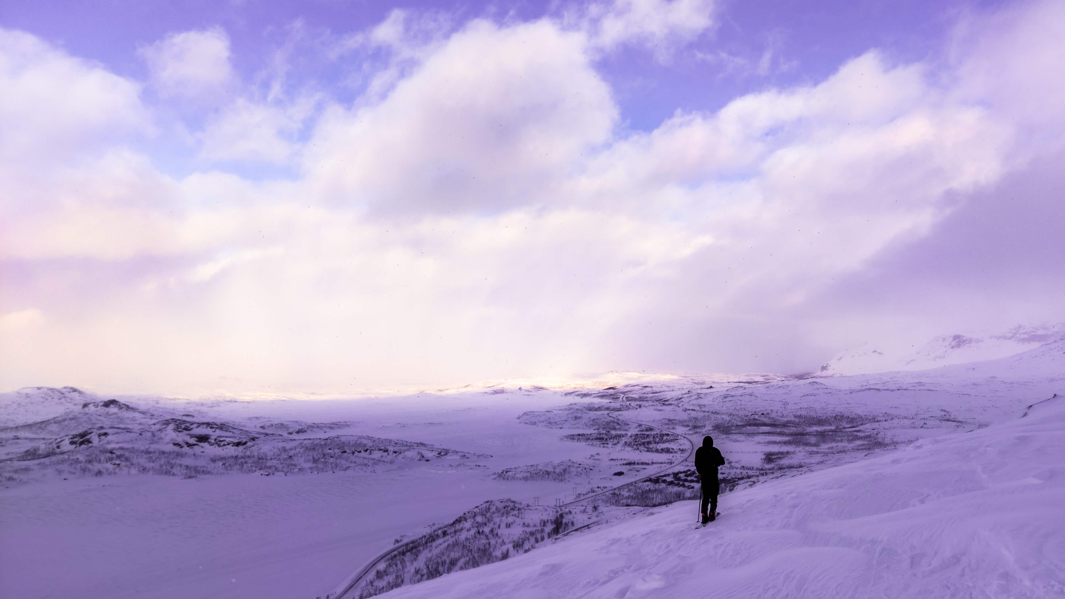 Vinterlandskap där en person star på sina skidor på bergssidan