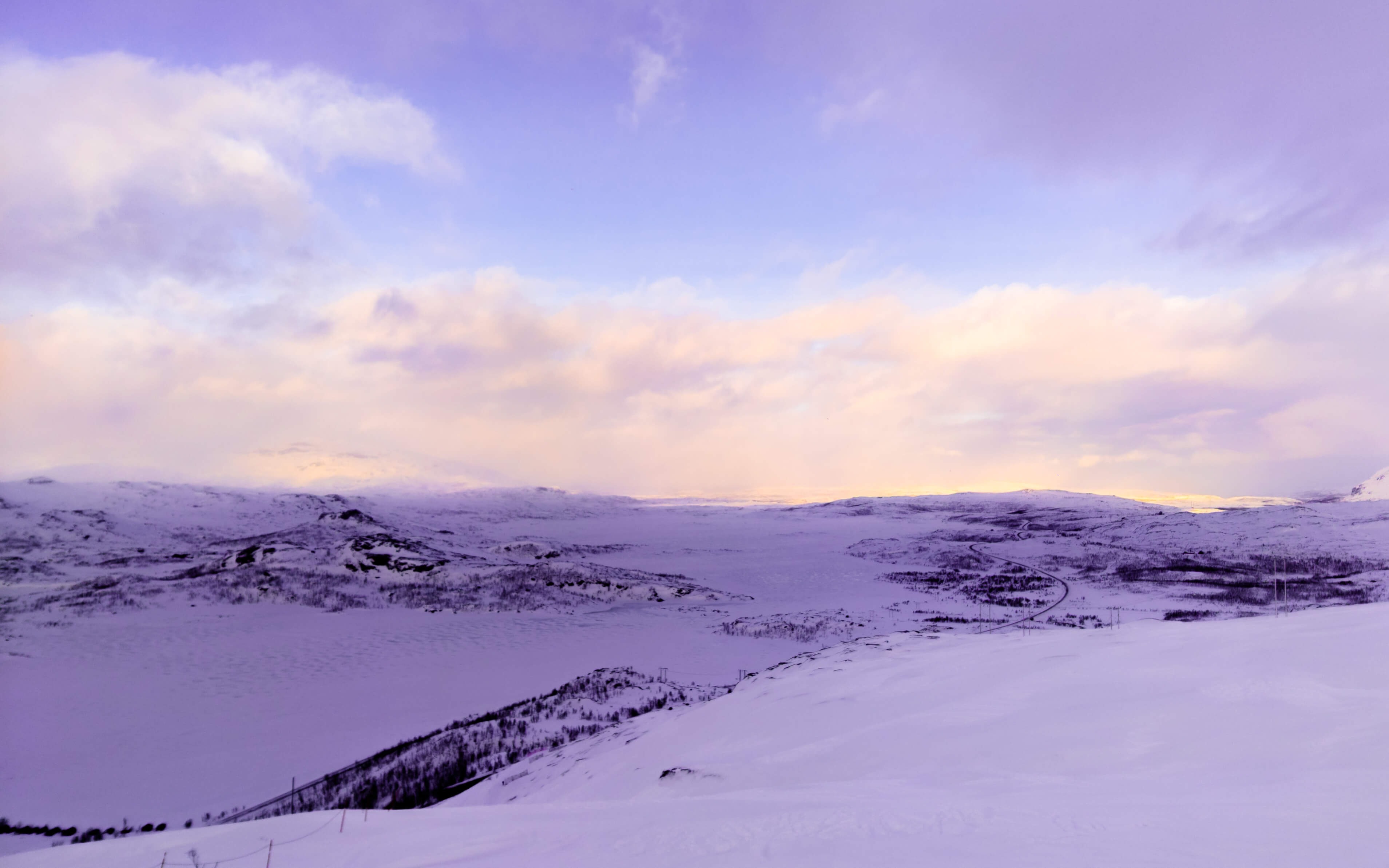 Photo from the top of a mountain in winter towards a valley with mountanous terrain on the other side